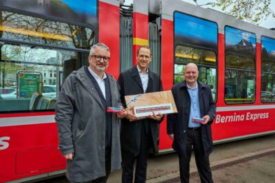 Slavnostní předání speciální tramvaje RhB s obřím curišským tirglem (tradiční perníkový výrobek) a miniaturní tramvají RhB. Ředitel VBZ Martin Sturzenegger, ředitel RhB Renato Fasciati a městský radní Michael Baumer (zleva doprava).